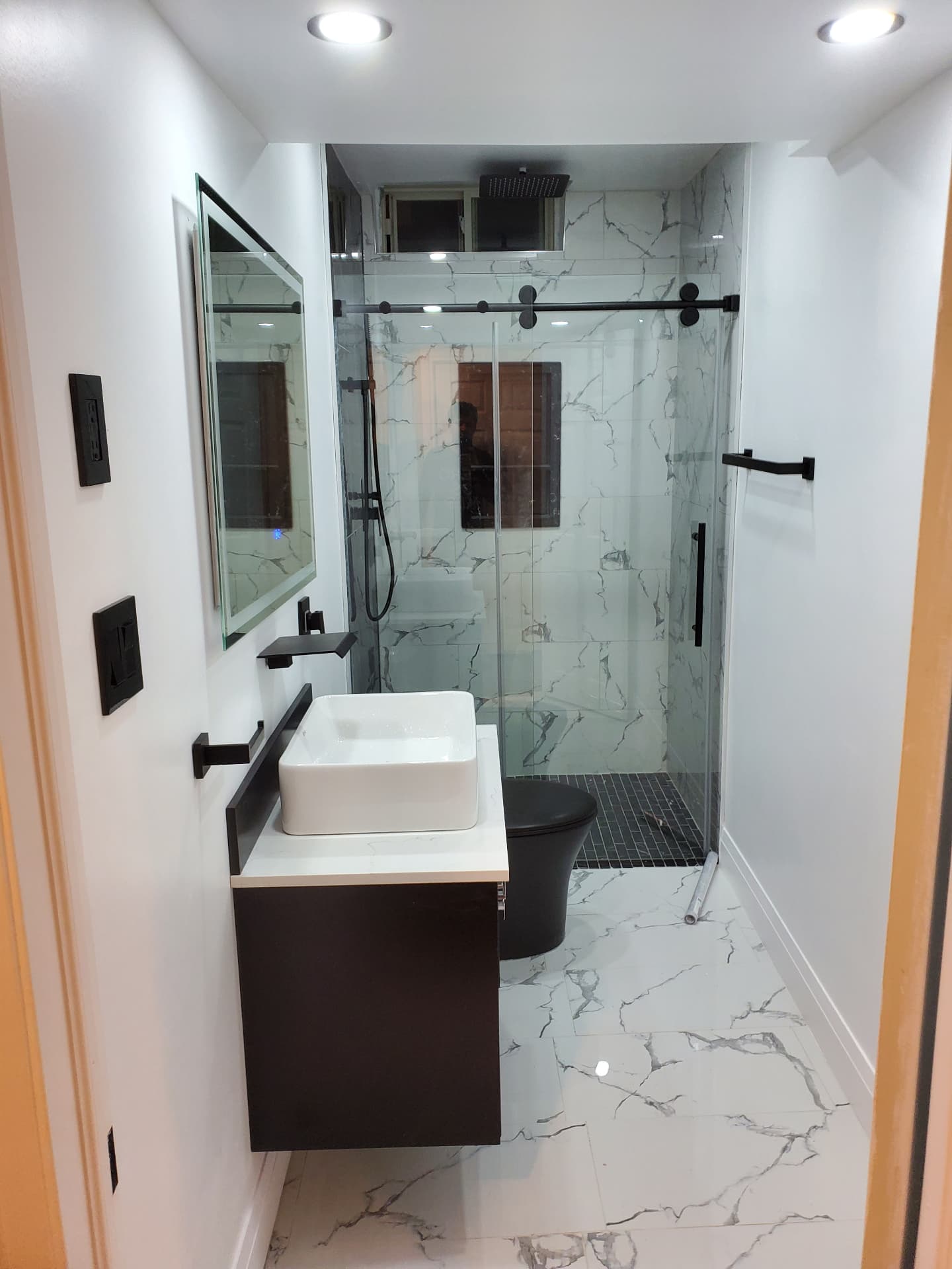 Completed basement bathroom with floating vanity, vessel sink and walk-in glass shower