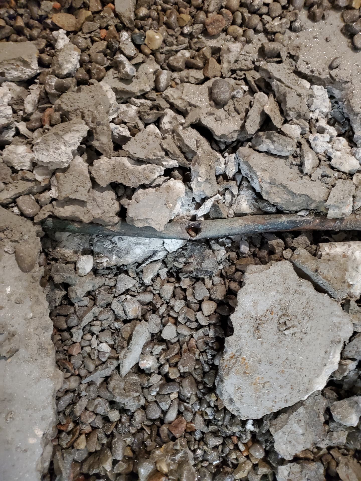 Excavated slab with exposed gravel and underground line