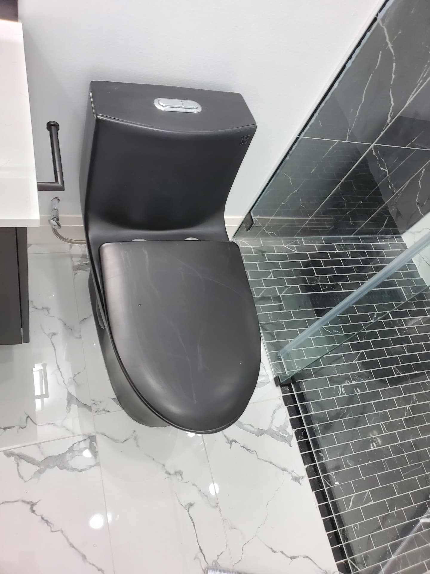 Completed modern basement bathroom with marble-look tile, floating vanity and glass shower