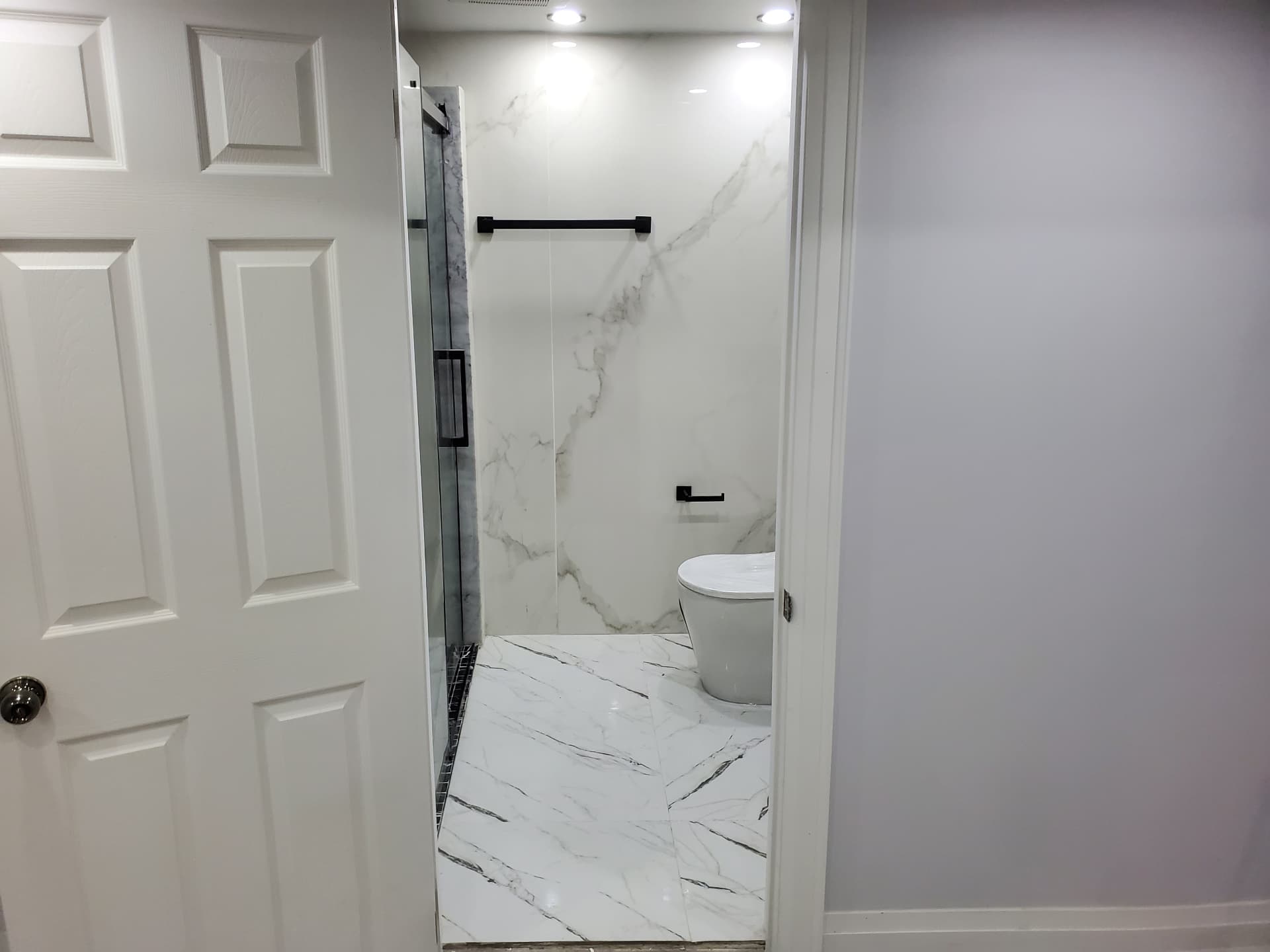 Bathroom entry with glass shower and marble-look tile
