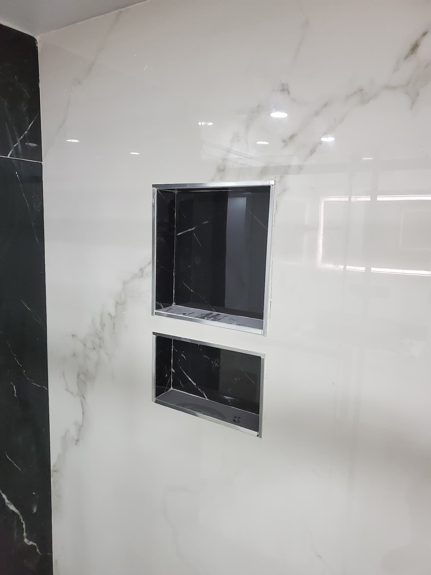 Recessed shower niches framed in the marble-look wall
