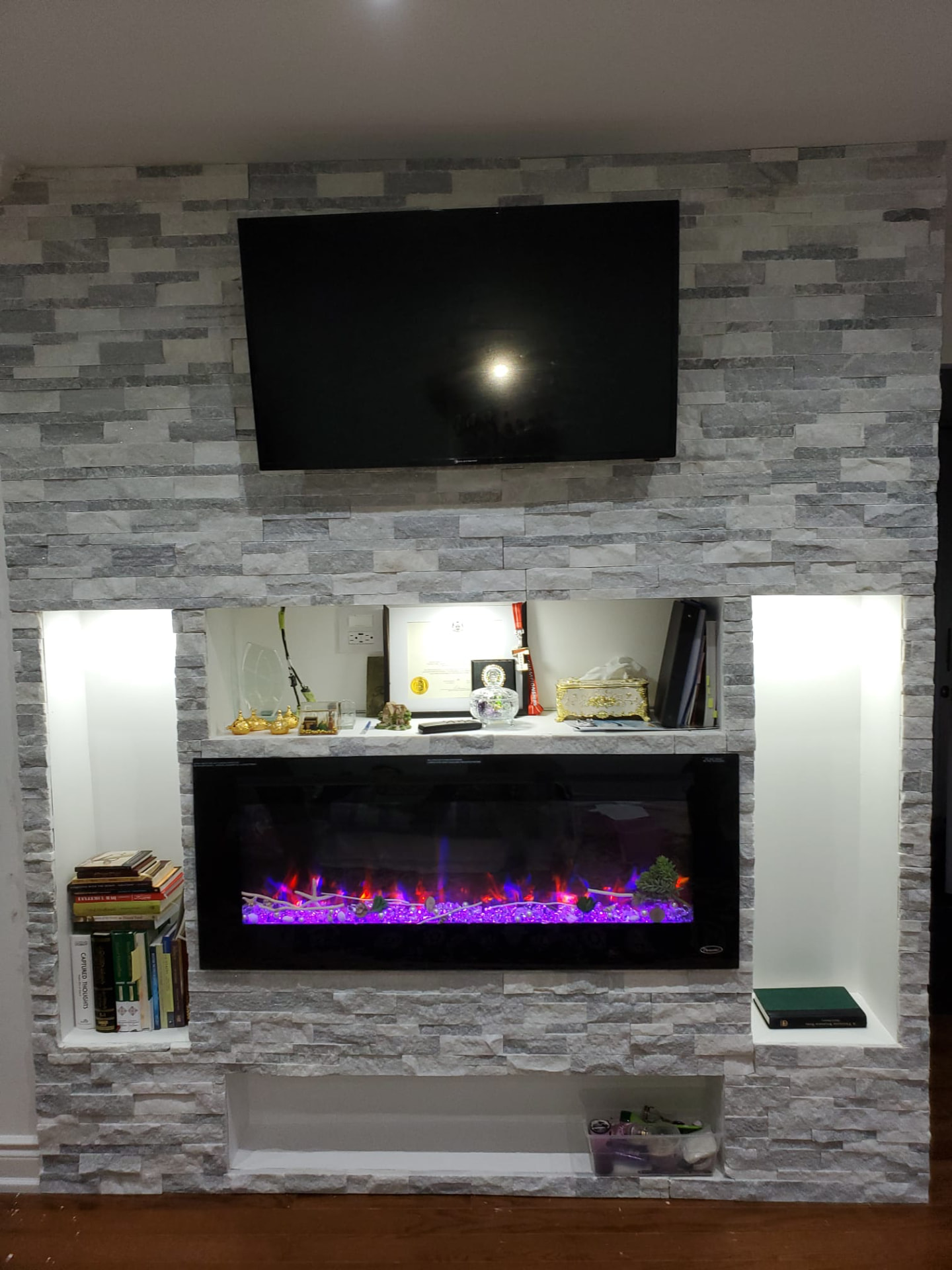 Feature wall progress with stacked stone installed around fireplace and niche openings